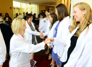 Ashlyn Bruning, director of clinical education at HPU, congratulates student Lindsay Webster on receiving her white coat.