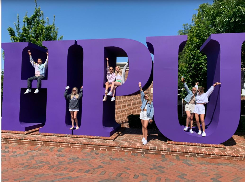 HPU letters with students sitting and standing on them