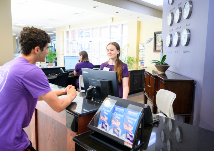 Student speaking with a campus concierge employee at a desk