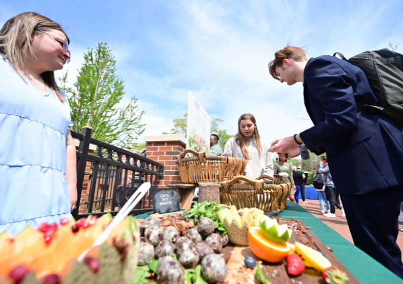 people by a table of fruit at HPU's Earth Day Celebration