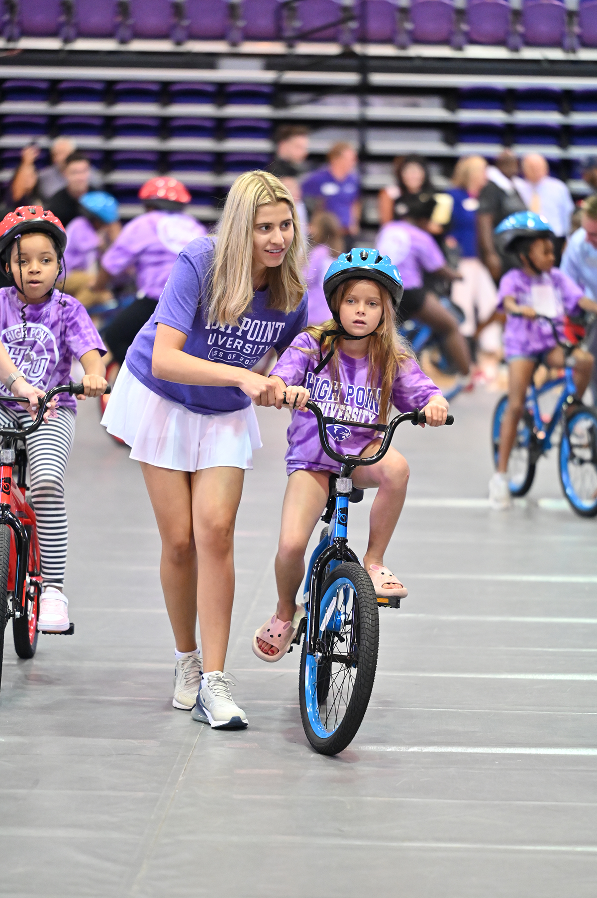 Pictured is Alexa Klein, a biology major from Baltimore, Maryland, helping a girl learn to ride her new bike.