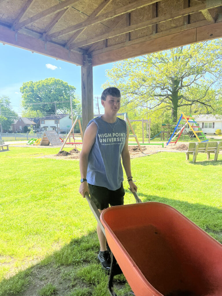 HPU Board of Stewards member Kody Lambeth uses a wheelbarrow while helping West End Ministries.
