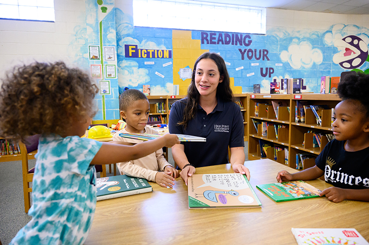 Lauren Brown, a freshman elementary education major from Seabrook, New Hampshire, interacts with kindergarten students as she reads aloud.
