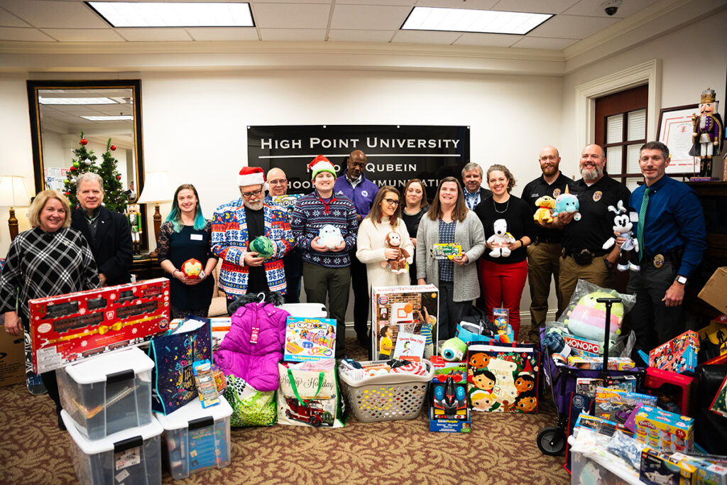 Pictured are High Point University faculty and staff in the Nido R. Qubein School of Communication, who partnered with deans of other academic schools and members of the Academic Leadership Council, to help local nonprofits provide Christmas gifts for families in need through their 11th annual Operation Elf tradition. They were joined by sport management major Brian Margolis, center, who heard about their effort and purchased gifts for children. 