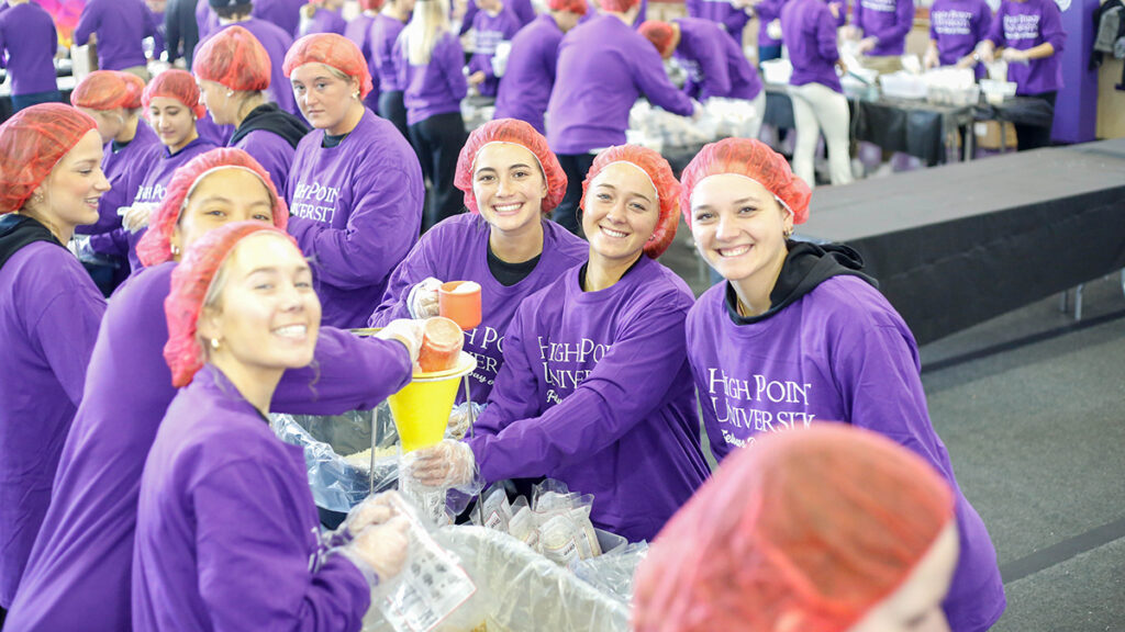 Students smile as they pack meals during the 2023 MLK Day of Service. 