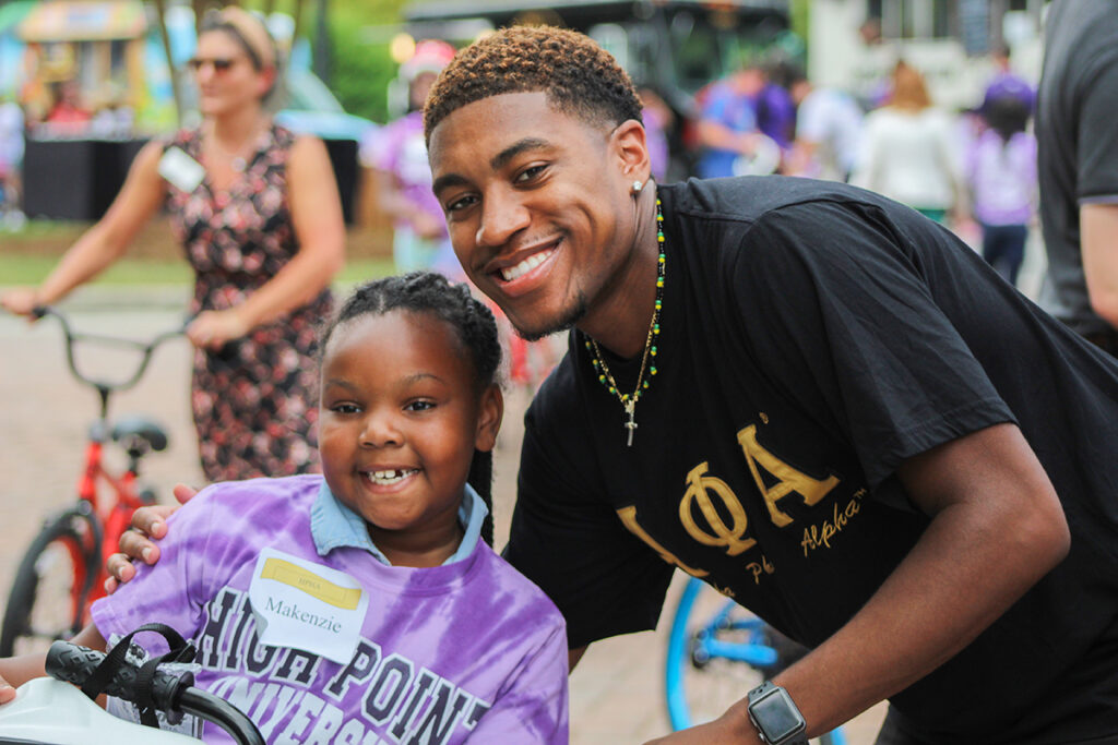 After receiving her bike, a local girl shares a smile with an HPU student. 3) An HPU student helps a local child to ride her bike for the first time.
