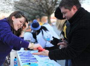 Civitan Club member Elizabeth Burns stamps the hands of participants at Friday’s camp out for the “Hands for the Homeless” banner created at the event.