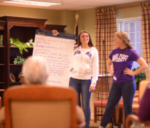 HPU students Ally Kane (left) and Jessie Drew lead one of many poetry writing sessions with residents at Pennybyrn at Maryfield in High Point through the HPU Lifelines program.