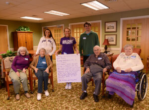 The students and senior citizens display one of their completed poems.