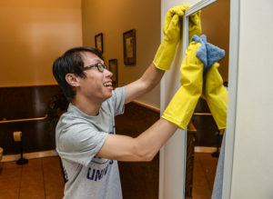 HPU student Steven Nguyen cleans a mirror at the Ritz Theatre on Washington Street in High Point. 